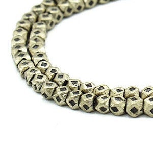 May include: A strand of gold-toned metal beads with a faceted, diamond-shaped design. The beads are strung on a wire and are approximately 6mm in diameter.