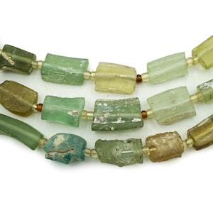 May include: A strand of antique glass beads in shades of green, yellow, and brown. The beads are rectangular and have a slightly irregular shape.