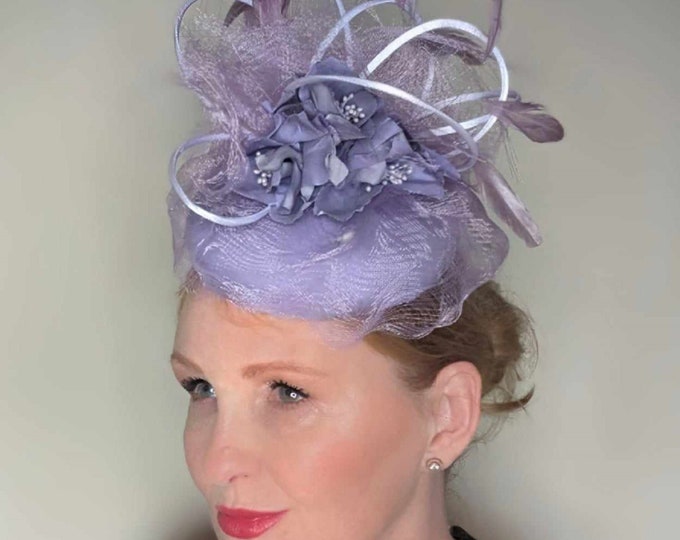 Beautiful silk button hat in shades of mauve and lilac. This stunning hat would look great for Ascot, ladies day races or mother of bride