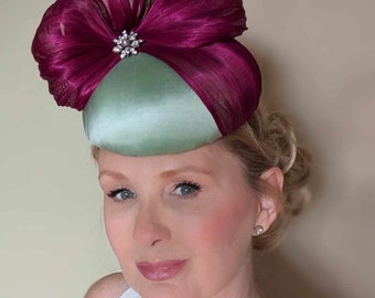 Pale mint green silk button hat decorated with magenta silk abaca. Perfect for Mother of the bride, Ascot or ladies day.