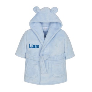 May include: A light blue hooded robe with bear ears, a tie belt, and two pockets. The robe is personalized with the name "Liam" embroidered on the front.