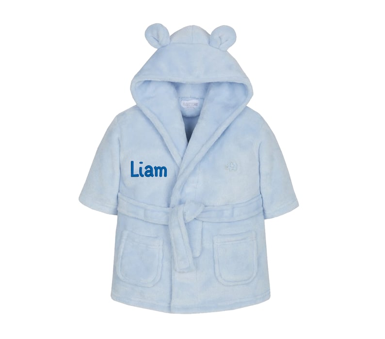 May include: A light blue hooded robe with bear ears, a tie belt, and two pockets. The robe is personalized with the name "Liam" embroidered on the front.