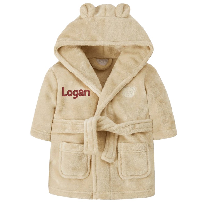 May include: A beige hooded robe with bear ears, a tie belt, and two pockets. The robe is embroidered with the name "Logan" in red.