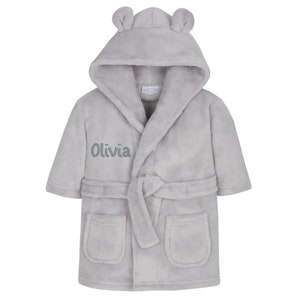 May include: Gray hooded robe with a tie belt and two pockets. The robe has bear ears on the hood and the name "Olivia" embroidered on the front.