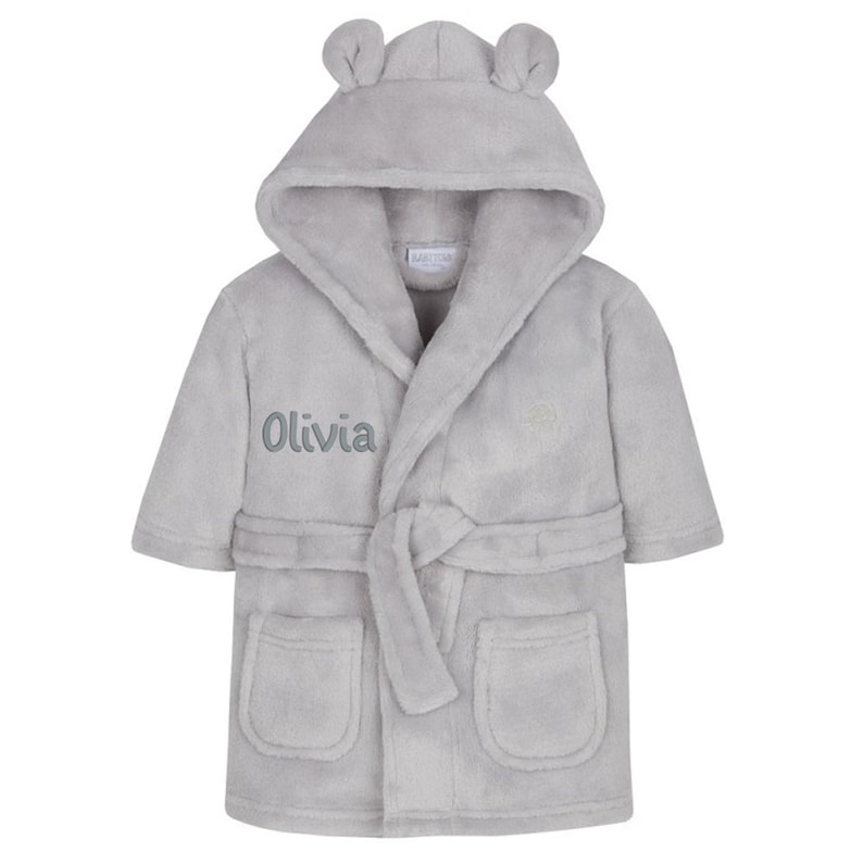 May include: Gray hooded robe with a tie belt and two pockets. The robe has bear ears on the hood and the name "Olivia" embroidered on the front.