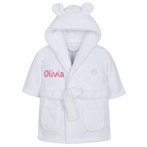 May include: White hooded bathrobe with a pink embroidered name "Olivia" and a small elephant logo. The robe has a tie belt and pockets.