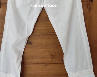 May include: White cotton pants with a white lace trim at the bottom. The pants have an elastic waistband and are FAB BOUTIQUE.