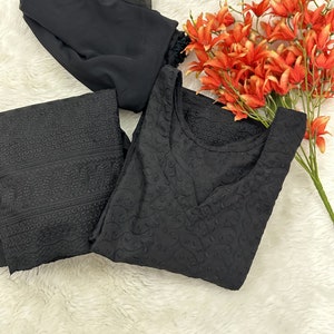 May include: Black embroidered dress and matching pants with a black sheer scarf. FAB BOUTIQUE is written in white text on a red background.