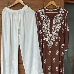May include: A brown embroidered kurta with white floral designs and a matching pair of white palazzo pants.