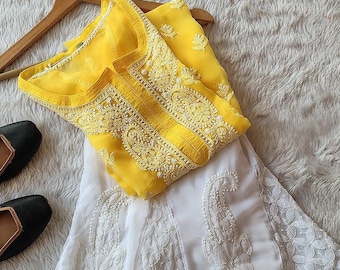 May include: A white and yellow embroidered dress set. The top is yellow with white embroidery and the skirt is white with white embroidery.