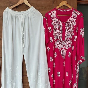 May include: A white embroidered palazzo pant and a pink embroidered kurta. The kurta has a white floral design and a V-neck.