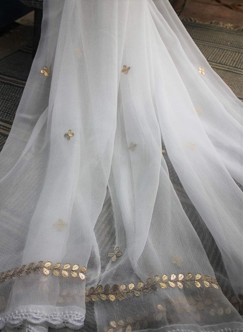 May include: White sheer scarf with gold embroidered floral designs and a gold leaf trim.