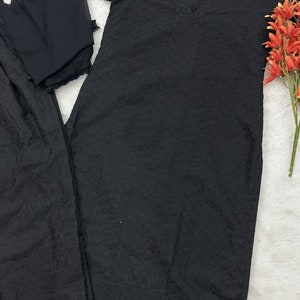 May include: Black embroidered three-piece suit with long sleeves and a round neckline. The suit includes a long top, pants, and a dupatta.