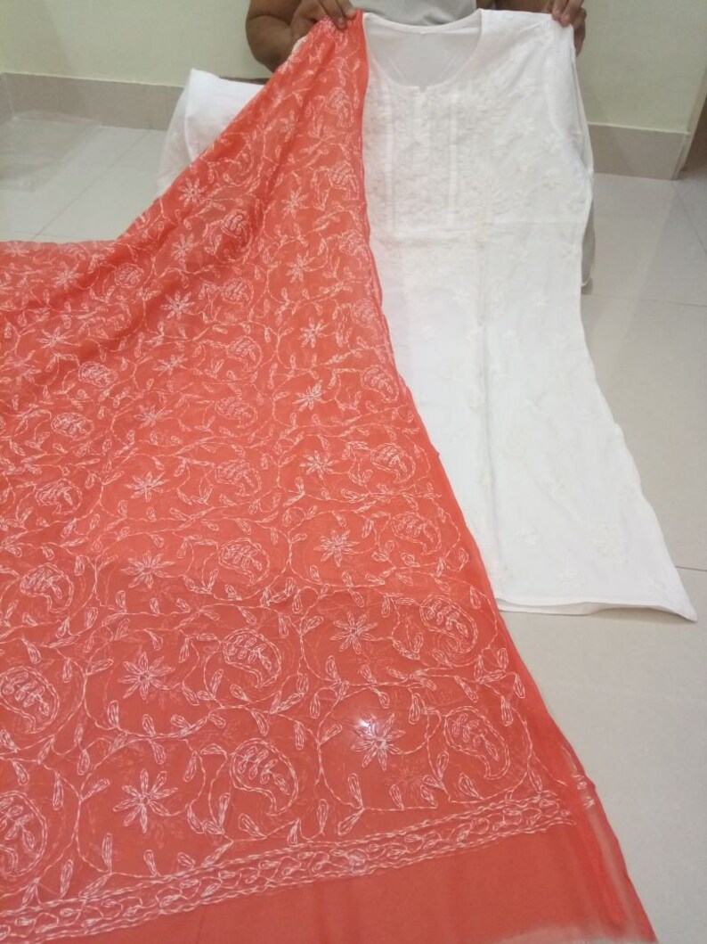 Op de afbeelding: Een witte katoenen kurta met borduurwerk en een bijpassende perzikkleurige dupatta met witte borduurwerk. De dupatta heeft een bloemenpatroon.