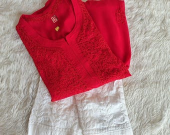 Puede incluir: Una blusa roja bordada con una falda bordada blanca. La blusa tiene un escote redondo y una pequeña etiqueta con la letra "M" en ella.
