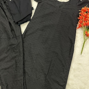 May include: A black embroidered three-piece suit with a long-sleeved top, pants, and a dupatta. The suit has a delicate floral pattern.