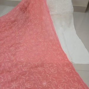 Op de afbeelding: Een roze, doorschijnende dupatta met witte borduursels. De dupatta heeft een bloemenpatroon en is gemaakt van een lichtgewicht stof.