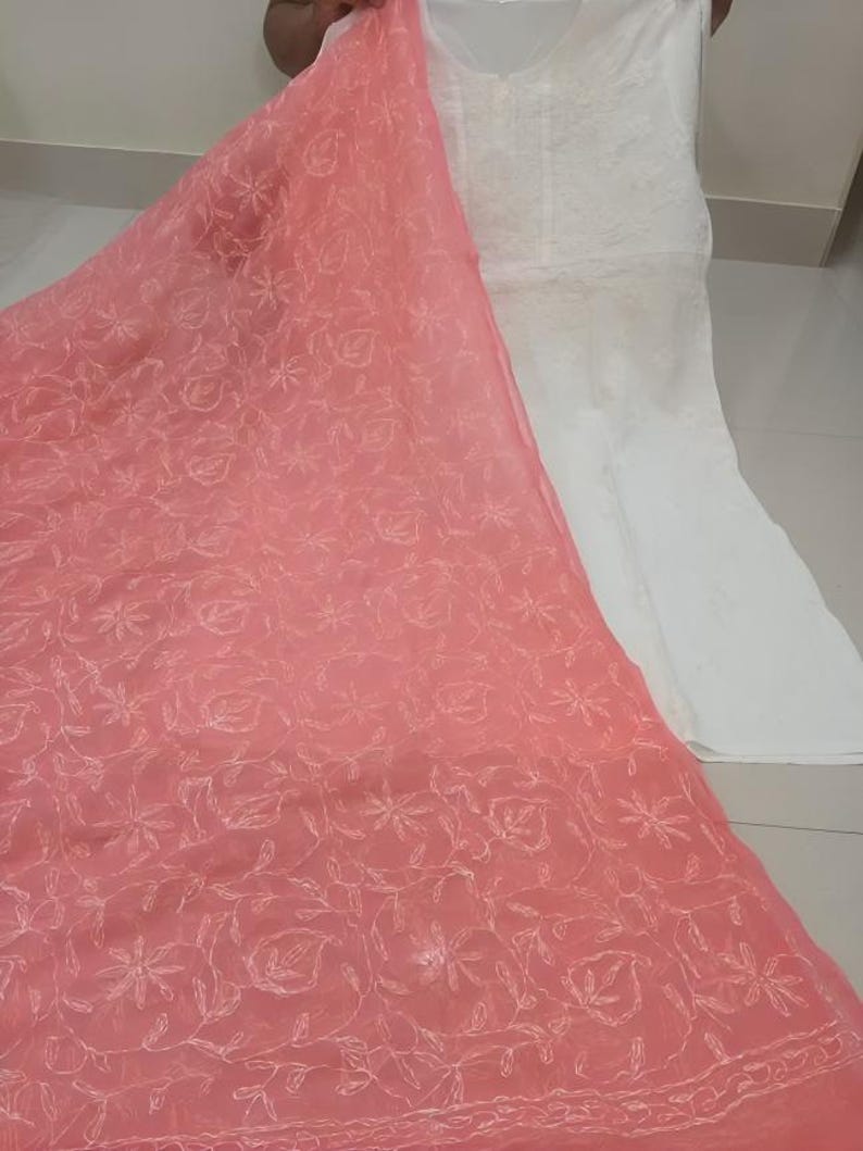 Op de afbeelding: Een roze, doorschijnende dupatta met witte borduursels. De dupatta heeft een bloemenpatroon en is gemaakt van een lichtgewicht stof.