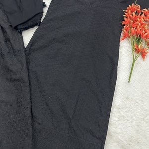 May include: Black embroidered dress with a matching dupatta. The dress has a round neckline and three-quarter sleeves. The dupatta is sheer and has a lace trim.
