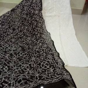 Op de afbeelding: Een witte katoenen kurta met zwarte borduursels, gecombineerd met een zwarte, doorschijnende dupatta met witte borduursels. De dupatta heeft een bloemenpatroon.