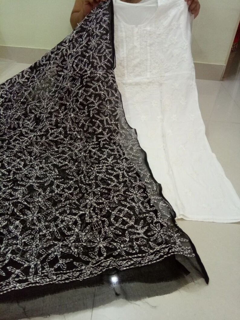Op de afbeelding: Een witte katoenen kurta met zwarte borduursels, gecombineerd met een zwarte, doorschijnende dupatta met witte borduursels. De dupatta heeft een bloemenpatroon.