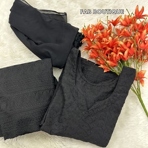 May include: Black embroidered dress and pants set with a matching black sheer scarf. The set features intricate floral patterns and a V-neckline. FAB BOUTIQUE is written in the top right corner of the image.