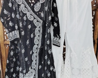 May include: A black wrap top and white palazzo trousers set. The black top has white paisley embroidery and a wrap design. The white palazzo trousers have a flared leg with matching embroidery. The set is displayed on wooden hangers.