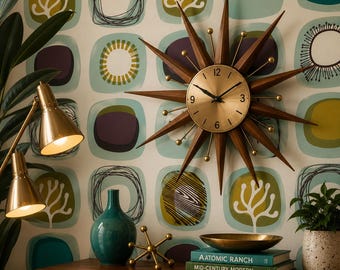 May include: A starburst wall clock with a gold-toned circular face and dark wood rays, featuring black hands and numerals. The clock is displayed against a patterned wallpaper with teal, olive, and purple shapes, alongside a gold lamp and books.