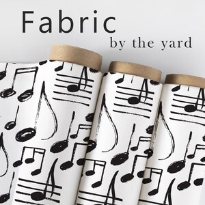 May include: White fabric with a black musical note pattern. The fabric is rolled up and labeled "Fabric by the yard".