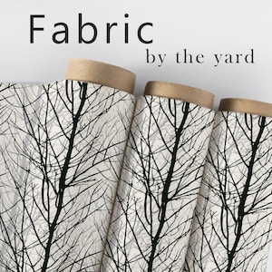 May include: Fabric by the yard. Rolls of fabric with a black tree branch pattern on a white background. The fabric is rolled on cardboard tubes with a tan color.