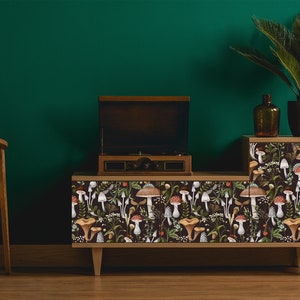 Dark botanical mushroom fabric peel and stick wallpaper on record player cabinet with plant and chair