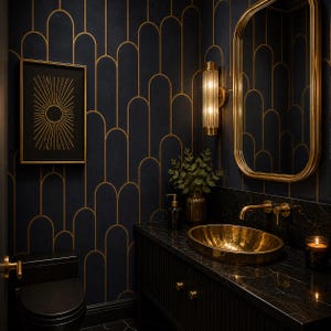 May include: A luxurious bathroom with a black and gold art deco theme. Features include a gold oval sink, a gold-framed mirror, and a black toilet. The walls are adorned with a dark blue wallpaper with gold arched patterns. A framed sunburst art piece hangs on the wall.
