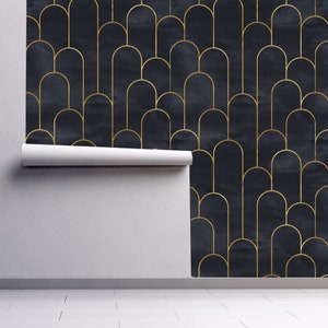 Moody dark Art Deco black and gold fabric peel and stick wallpaper on wall partially rolled up