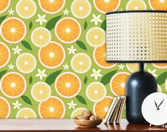 May include: A green wallpaper with a repeating pattern of orange slices and white flowers. A black lamp with a woven shade sits on a wooden table in front of the wallpaper.