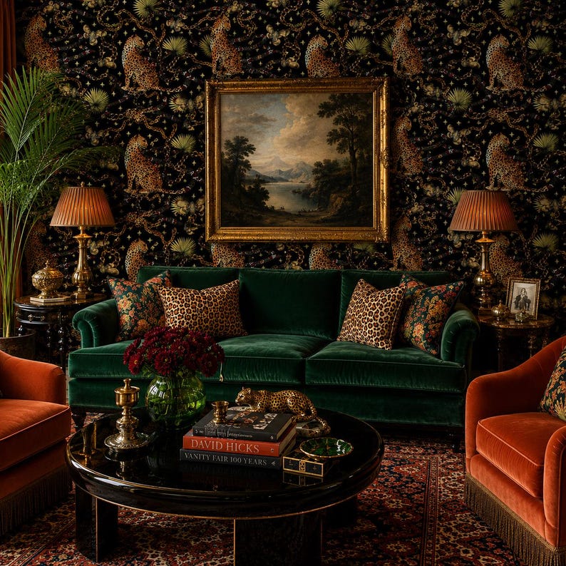 May include: A dark green velvet sofa with leopard print pillows, positioned in front of wallpaper featuring leopards and gold chains. A black coffee table holds books titled David Hicks and Vanity Fair 100 Years, with a gold leopard figurine.