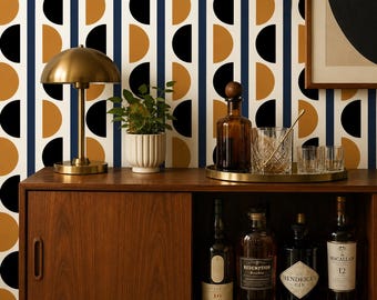 May include: A mid-century modern bar cabinet with a brass lamp, a small potted plant, and a tray with glassware and a bottle. The cabinet is made of wood and has a sliding door. The background is a wallpaper with a geometric pattern.