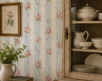 May include: A vintage-style interior scene featuring a wooden cabinet with glass doors, displaying white dishware. The wallpaper has a cream background with vertical light blue stripes and pink rose floral patterns. A framed botanical print and a vase with flowers are on a wooden table.