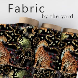 May include: Black fabric with a repeating pattern of gold chains, black snakes, green palm leaves, and orange leopards. The fabric is labeled "Fabric by the yard".
