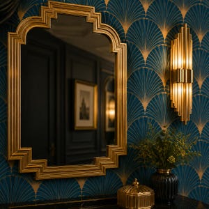 May include: A gold-framed mirror with an Art Deco design hangs on a wall with a blue and gold fan pattern. A matching gold sconce and decorative items complete the elegant interior design.
