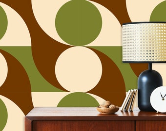 May include: A brown, green, and cream geometric patterned wallpaper with a black lamp with a woven shade, a white clock, and a wooden table with a bowl of walnuts.