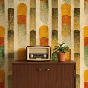 May include: A vintage-style radio with a cream-colored face and brown trim sits atop a dark wood cabinet. A small potted plant is to the right. The background is a colorful, abstract pattern of vertical shapes in shades of yellow, orange, and green.