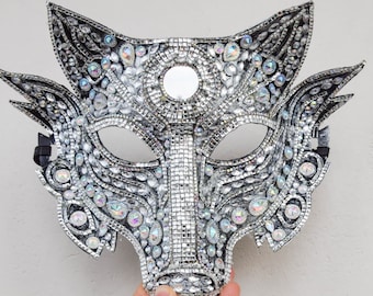 May include: A silver wolf mask with iridescent rhinestones and a mirrored center piece.