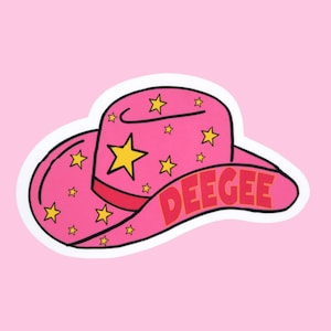 May include: A pink cowboy hat sticker with yellow stars and the word "DEEGEE" in red letters. The hat has a white border and is set against a pink background. The hat's design includes a large yellow star on the front.