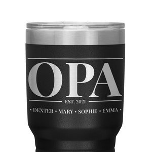 May include: Black stainless steel tumbler with a white inscription that reads "OPA EST. 2021 DEXTER MARY SOPHIE EMMA".