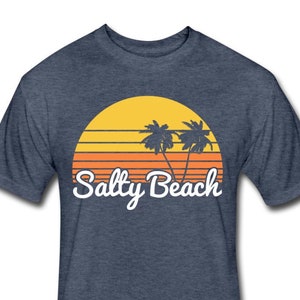 May include: A navy blue t-shirt with a retro sunset graphic featuring two palm trees and the text "Salty Beach" in white.