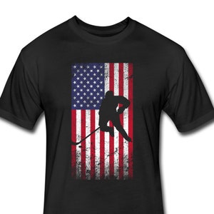 May include: Black t-shirt with a distressed American flag design and a silhouette of a hockey player skating with a stick.