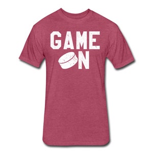 May include: A heather red t-shirt with a white graphic that says "GAME ON" with a hockey puck graphic.