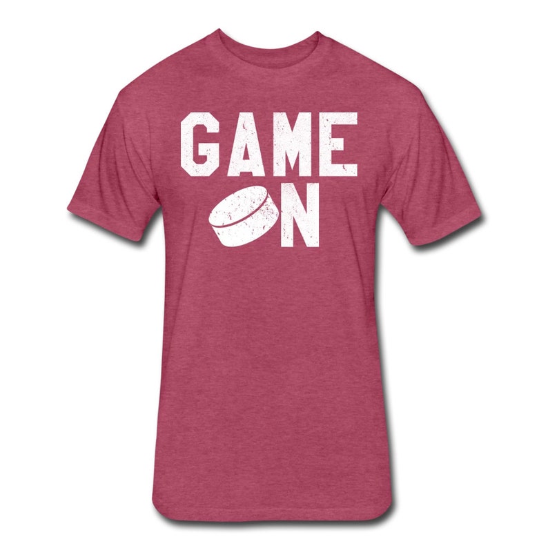 May include: A heather red t-shirt with a white graphic that says "GAME ON" with a hockey puck graphic.