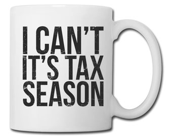 Puede incluir: Taza de café de cerámica blanca con texto negro que dice "I CAN'T IT'S TAX SEASON".