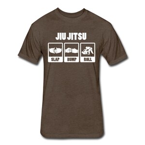 May include: A brown t-shirt with the text "JIU JITSU" in white letters. Below the text are three white boxes with illustrations of hands slapping, bumping, and rolling, with the words "SLAP", "BUMP", and "ROLL" underneath each illustration.